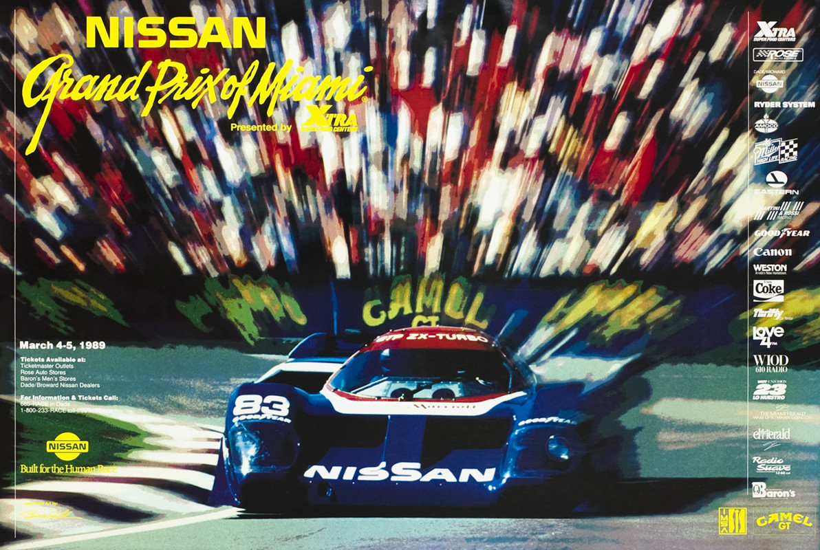 Nissan racecar zooms forward, background blurred behind; blue, red, yellow, black
