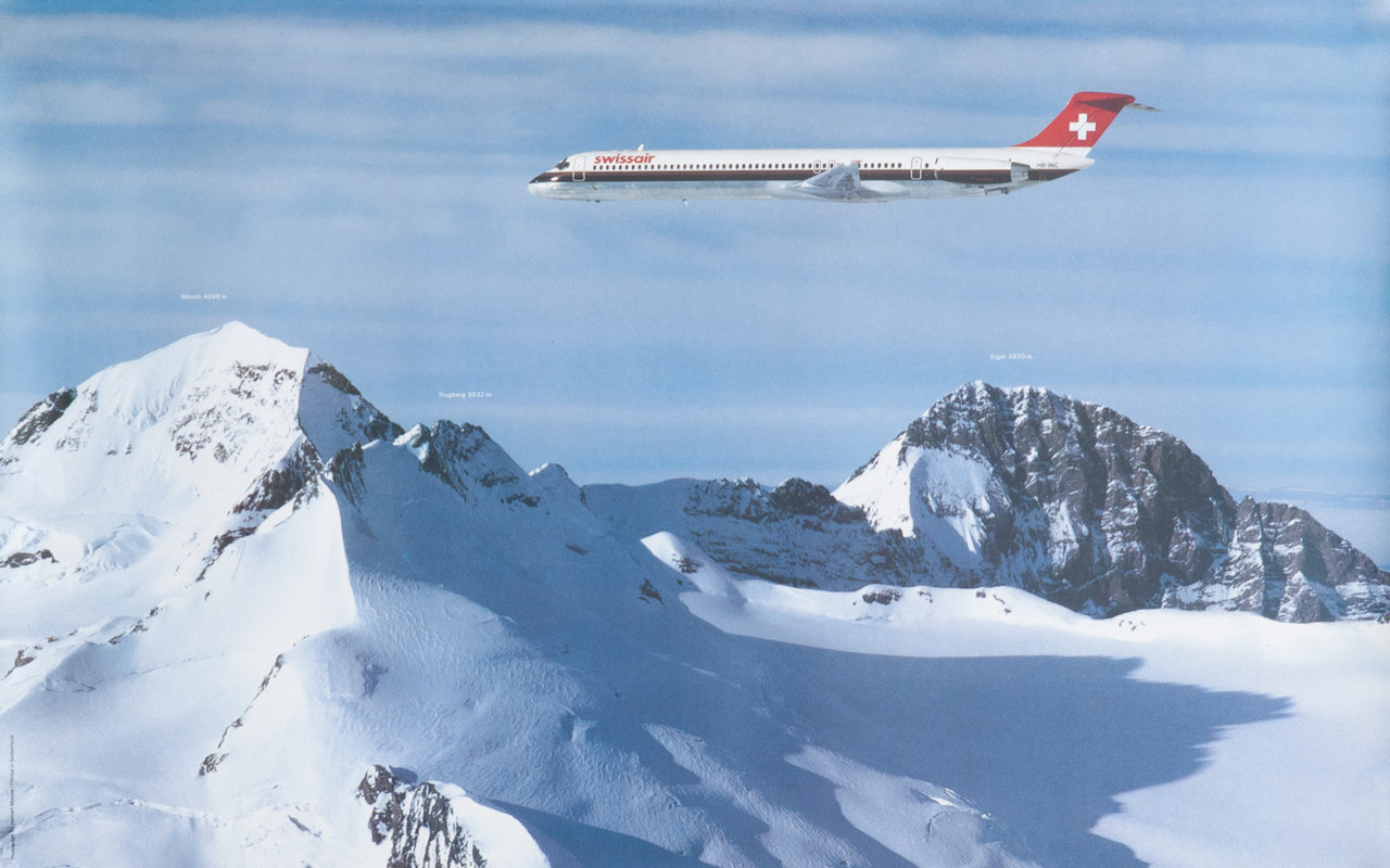 Swissair plane flying over Monch, Eiger, and Trugburg mountains in the Swiss Alps; blue, red, white, black