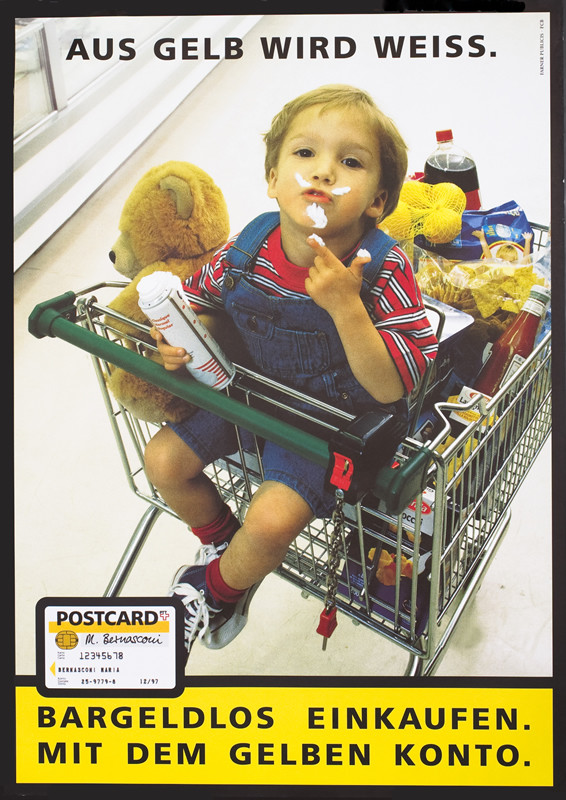 Boy in grocery carriage frosting on face; white, blue, yellow