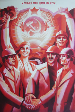 Woman and men in hard hats join hands under hammer and sickle; red, yellow, black