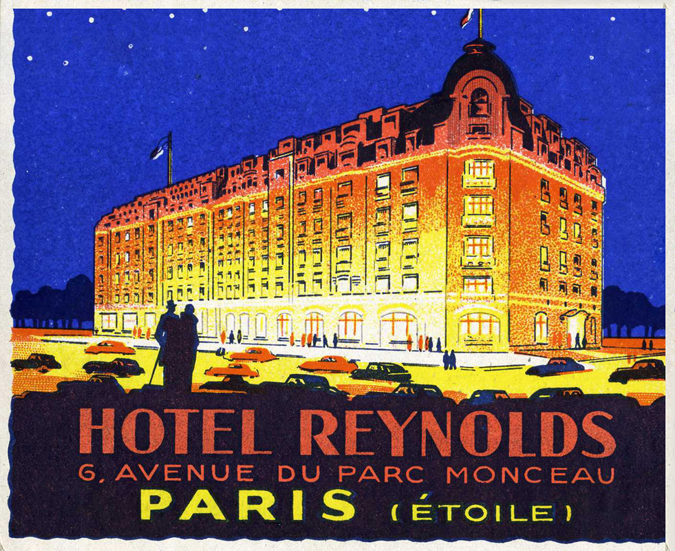 Glowing hotel alongside boulevard filled with cars; yellow, red, orange, blue