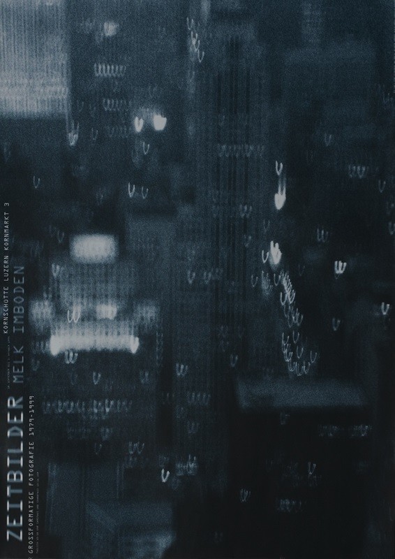 Blurry photograph of cityscape; gray, white, black